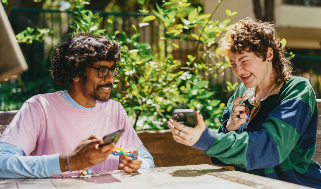 Two people laughing and discussion something on their phones