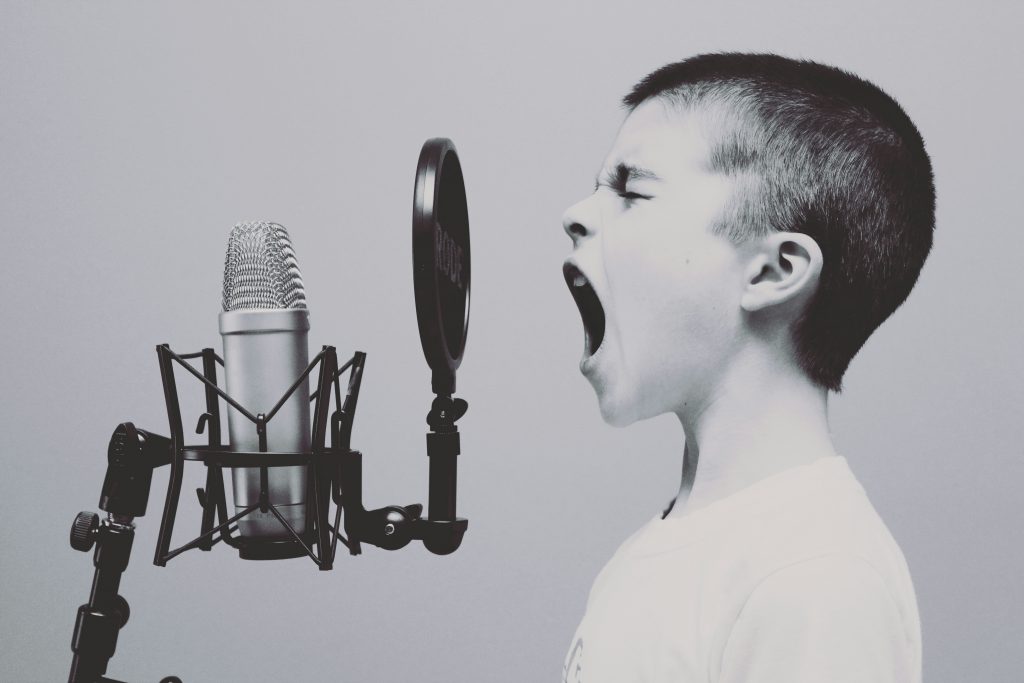 Young boy screaming into a microphone