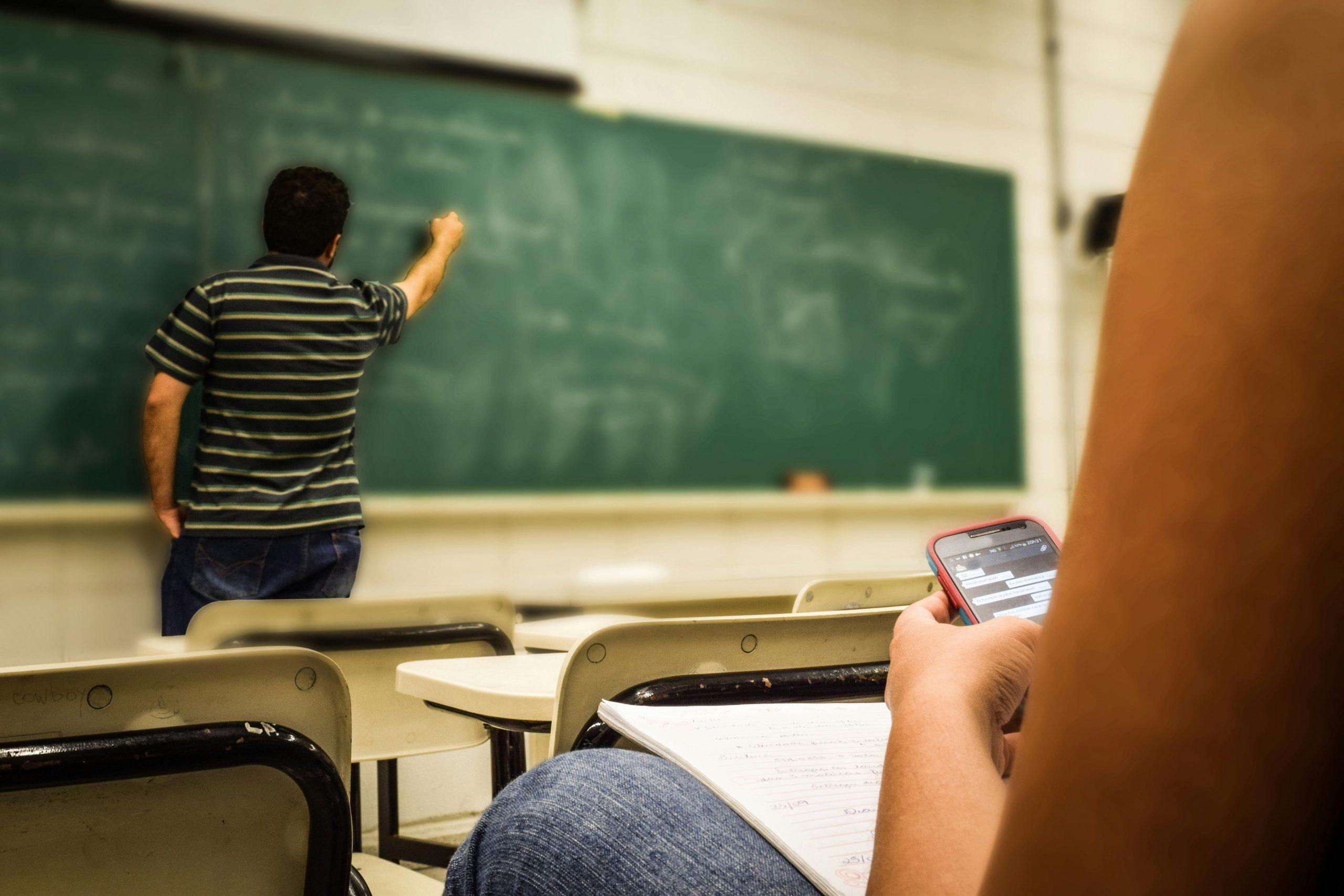 Image of child on mobile phone distracted in classroom