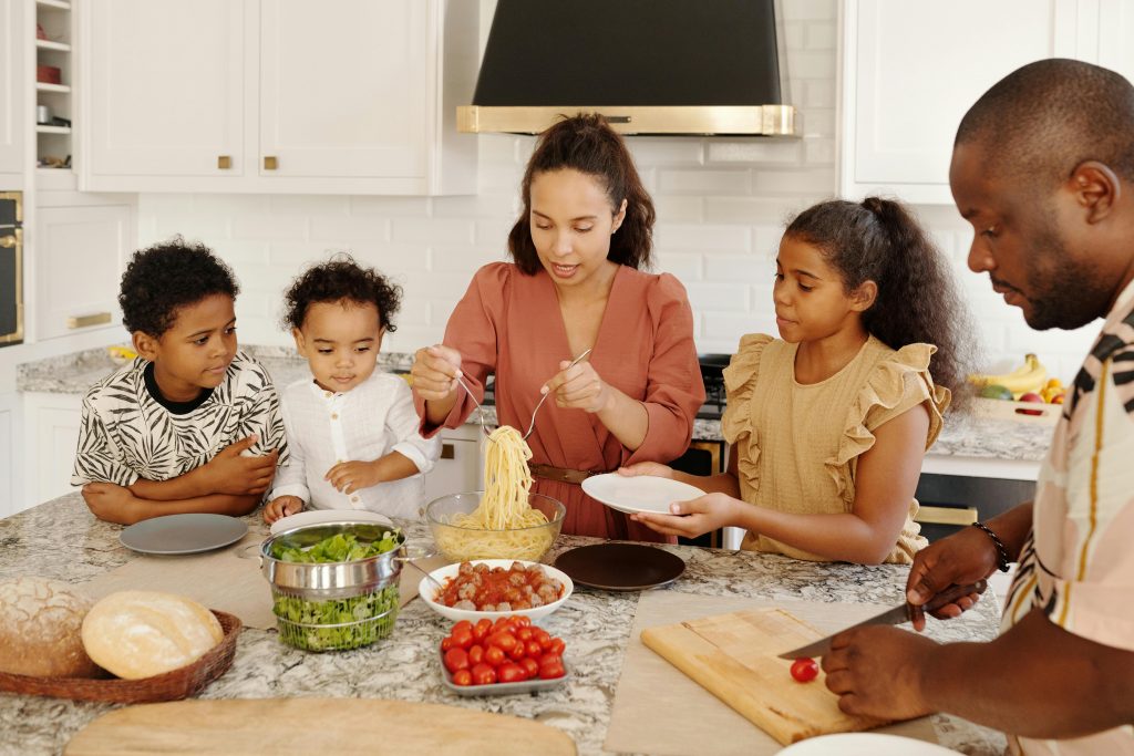 Two adults and three children preparing food at the table